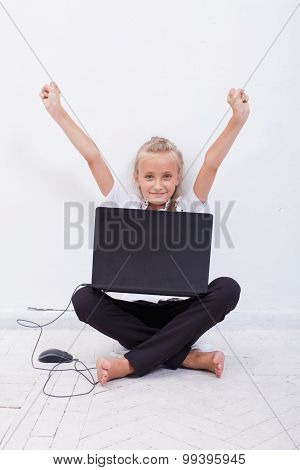 young teen girl with arms raised using laptop