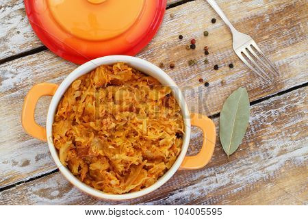 Polish bigos in saucepan on rustic wooden surface