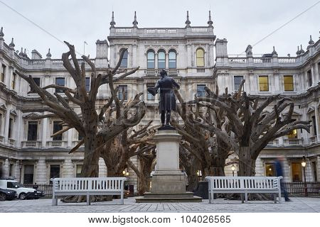 LONDON, UK - SEPTEMBER 23: Statue of Sir Joshua Reynolds amongst Ai Wei Wei's installation 'Tree' in the forecourt of the Royal Academy of Arts. September 23, 2015 in London.