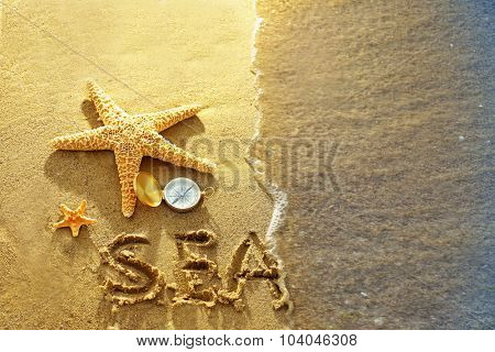 Compass with sea stars on sand beach background