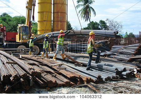 Group of construction workers lifting bundle of reinforcement bar using crane