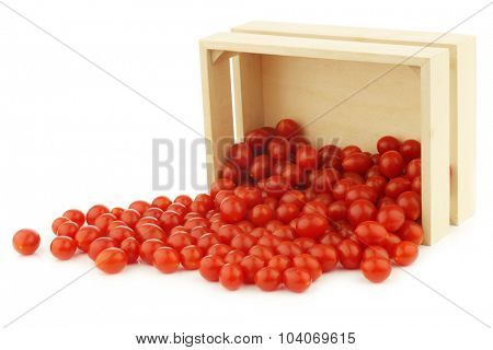 fresh Tomberry (very small) tomatoes in a wooden crate on a white background