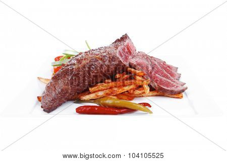 meat and potato : rare grilled beef steak served with pepper and tomato over plate isolated on white background