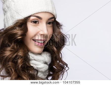 Beautiful girl with gentle makeup, curls and smile in white knit hat. Warm winter image. Beauty face