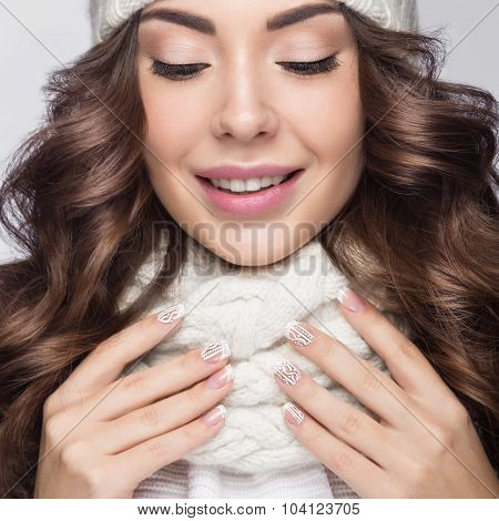 Beautiful girl with gentle makeup, design manicure and smile in white knit hat. Warm winter image. B