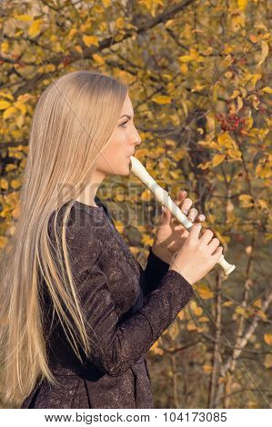 Beautiful Young Blonde Woman Playing Flute Recorder In Autumn Forest