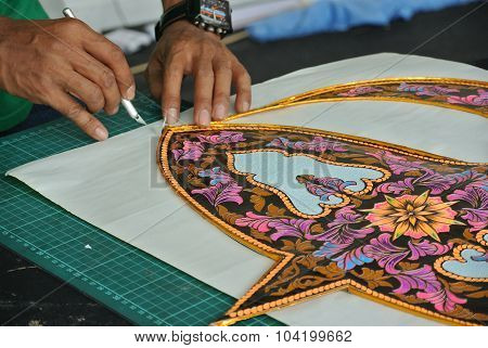 Malaysian kite maker working on a kite in his workshop