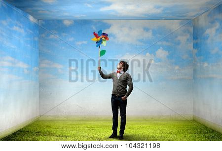 Young happy guy in casual with colorful windmill in hand