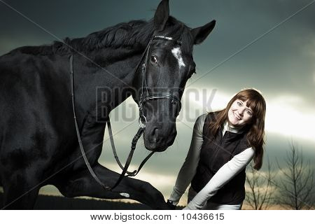 Hermosa joven con un caballo negro