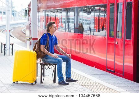 Young man with baggage at a train station near express