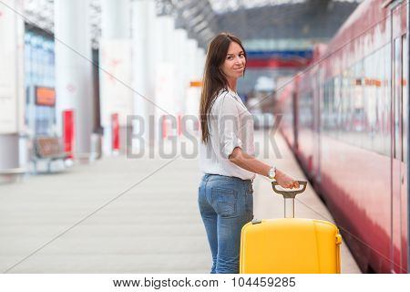 Young woman with luggage on train platform waiting for aeroexpress