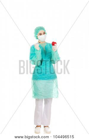 Young female cardiologist surgeron holding heart and scalpel.