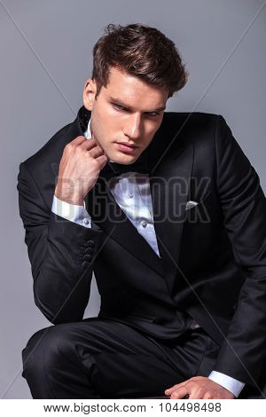 Elegant young business man looking down while fixing his ollar.