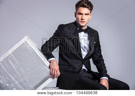 Business man sitting while leaning on a white table wrapped in plactic foil.
