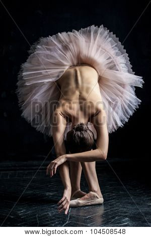 Beautiful ballerina  posing leaning on dack background