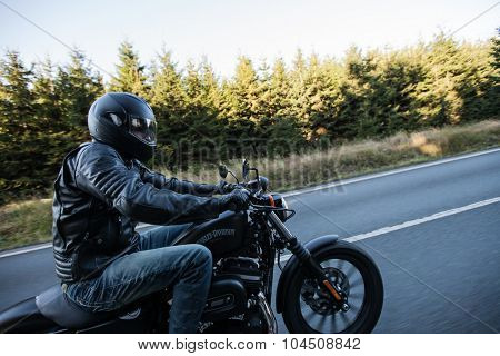 ROUSINOV - SEPTEMBER 29: Harley-Davidson Motorcycle Sportster Iron 883, drives through the forests during sunrise. September 29, 2015 in Rousinov, Czech republic.