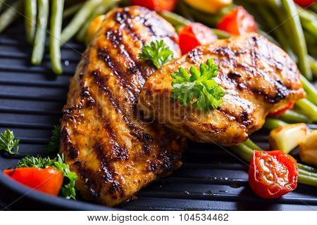 Grilled chicken breast in different variations with cherry tomatoes, green French beans, garlic