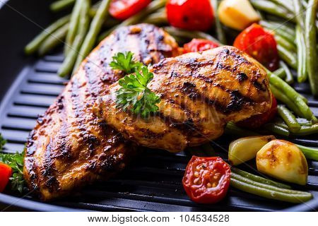 Grilled chicken breast in different variations with cherry tomatoes, green French beans, garlic