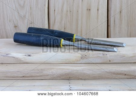 Two Chisels With Black Handles Lying On Wooden Boards