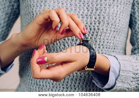 Women's Hands With Bright Manicure Fastens The Strap On The Watch