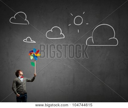 Young happy guy in casual with colorful windmill in hand