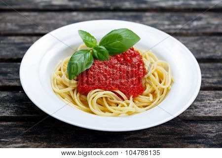Spaghetti With Marinara Sauce And Basil Leaves On Top, On Wooden Table.
