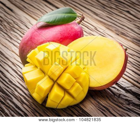 Mango fruit and mango cubes on the wooden table.