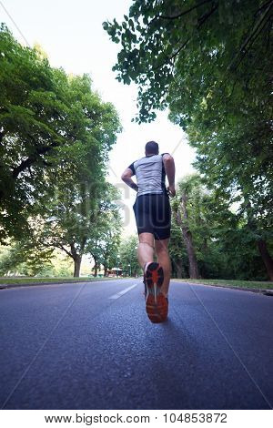 healthy athlete man jogging at morning on empty  roat in the city