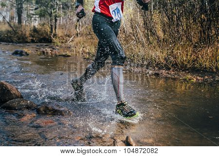 feet closeup male runner crossing river on rocks