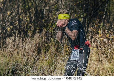 runner man drinks water from a mountain stream