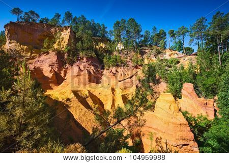 Unique red and orange hills in the province of Languedoc - Roussillon, France. Green trees create a beautiful contrast with the bright ocher