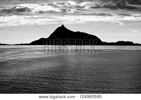 Black And White Norwegian Landscape At Sunset With The Sea Water, Cloudy Sky And Fjord Mountain In T