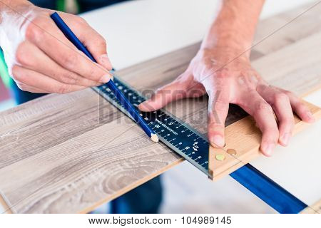 Carpenter marking cut on parquet piece 