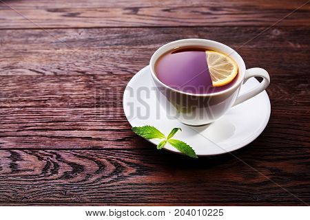 Green tea with lemon and mint on wooden table background with copy space