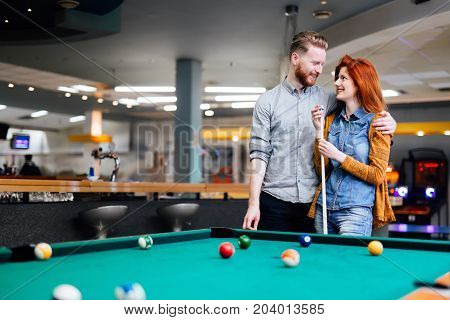 Happy couple playing snooker and billiards at club
