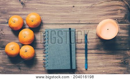 Book, pencil, mandarins and candle on the wood background