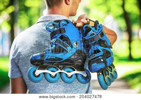 Young Male Roller Skater Holding Inline Roller Skates.