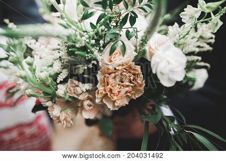 Beauty wedding bouquet with different flowers in hands.