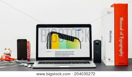 PARIS FRANCE - SEP 3 2017: Minimalist creative room table with Safari Browser open on MacPook Pro laptop showcasing Apple Computers website with latest iPhone X 10 with TrueDepth camera close-up