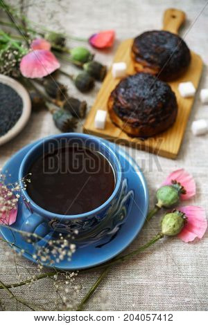 a fine breakfast a mug of tea fresh rolls with poppy seeds and poppy flowers.