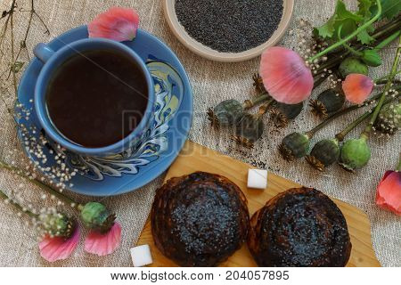 a fine breakfast a mug of tea fresh rolls with poppy seeds and poppy flowers.