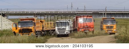 Kazakhstan, Ust-Kamenogorsk, august 18, 2017: Dump trucks Kamaz and Shacman stopped in the steppe next to the railway bridge