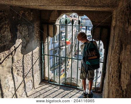 Oporto, Portugal - july 2016: Child look out from the Iron Barriers inside Clerigos Tower (Torre dos Clerigos) in the Center of Porto Portugal