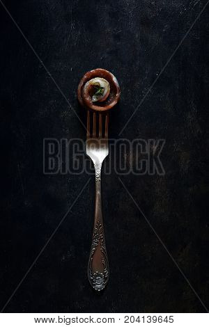 appetizing appetizer of slightly salted saury in the form of a roll on the fork
