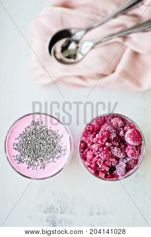 Chia and frozen raspberies cottage cheese breakfast in two small transparent glasses