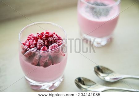 Chia and frozen raspberies cottage cheese breakfast in two small transparent glasses