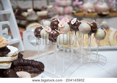 Chocolate cake pops covered in milk and white chocolate decorated with pink edible marzipan flowers