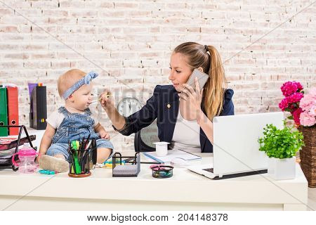Family Business - telecommute Businesswoman and mother with kid is making a phone call. At the workplace, together with a small child