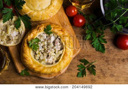 Round meat pie with vegetables and spices on a wooden background. Selective focus.