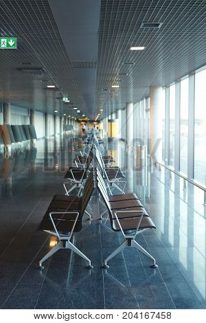 Empty airport terminal waiting area with chairs. passenger seat in Departure lounge for see Airplane, view from airport terminal. transport and travel concept